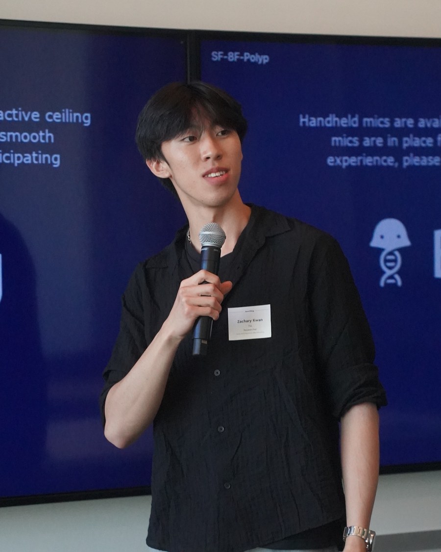 Zachary Kwan speaking into a handheld mic